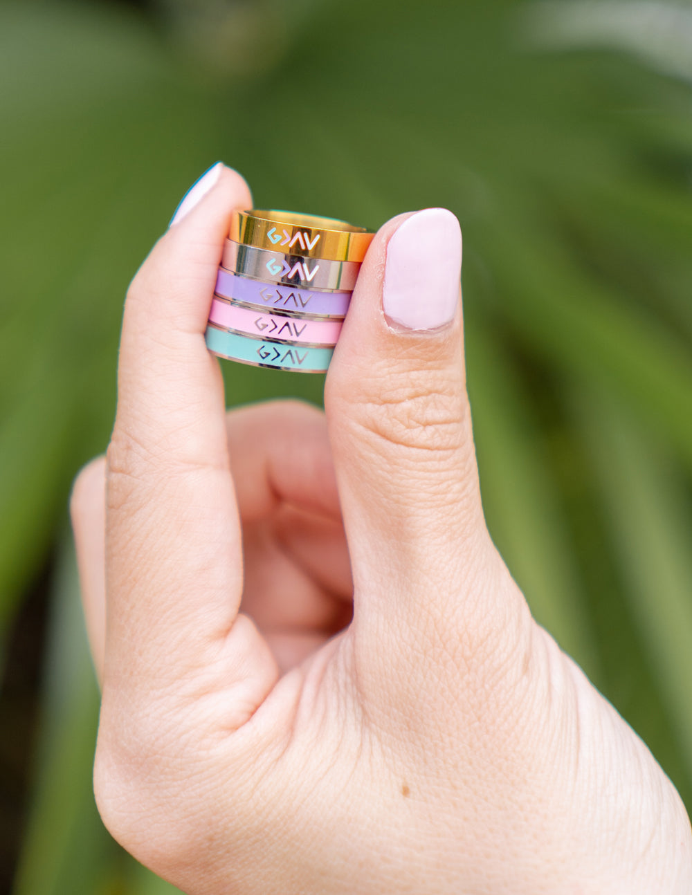 Gold enamel rings on fingers, blue-green logo marks on band