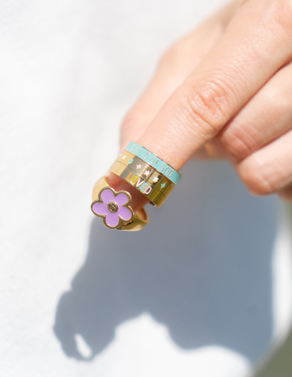 Gold ring with turquoise enamel band and purple clover charm, worn on finger