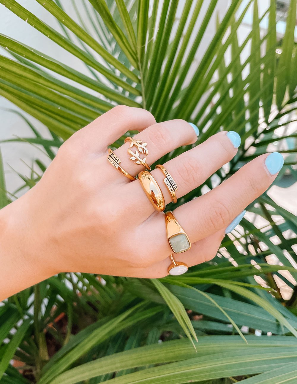 Gold-tone olive branch ring with small leaves and branch detail, worn on hand.