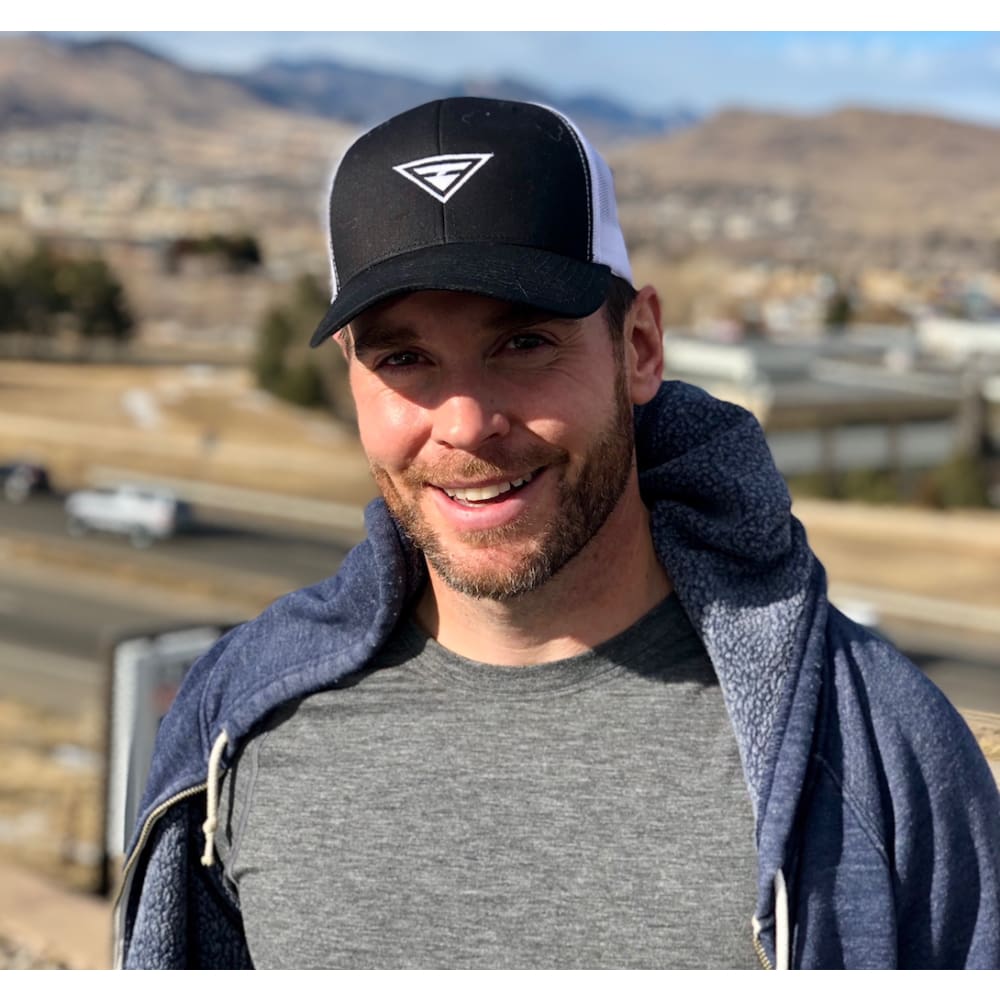 Black trucker snapback hat with white embroidered triangle logo on a man