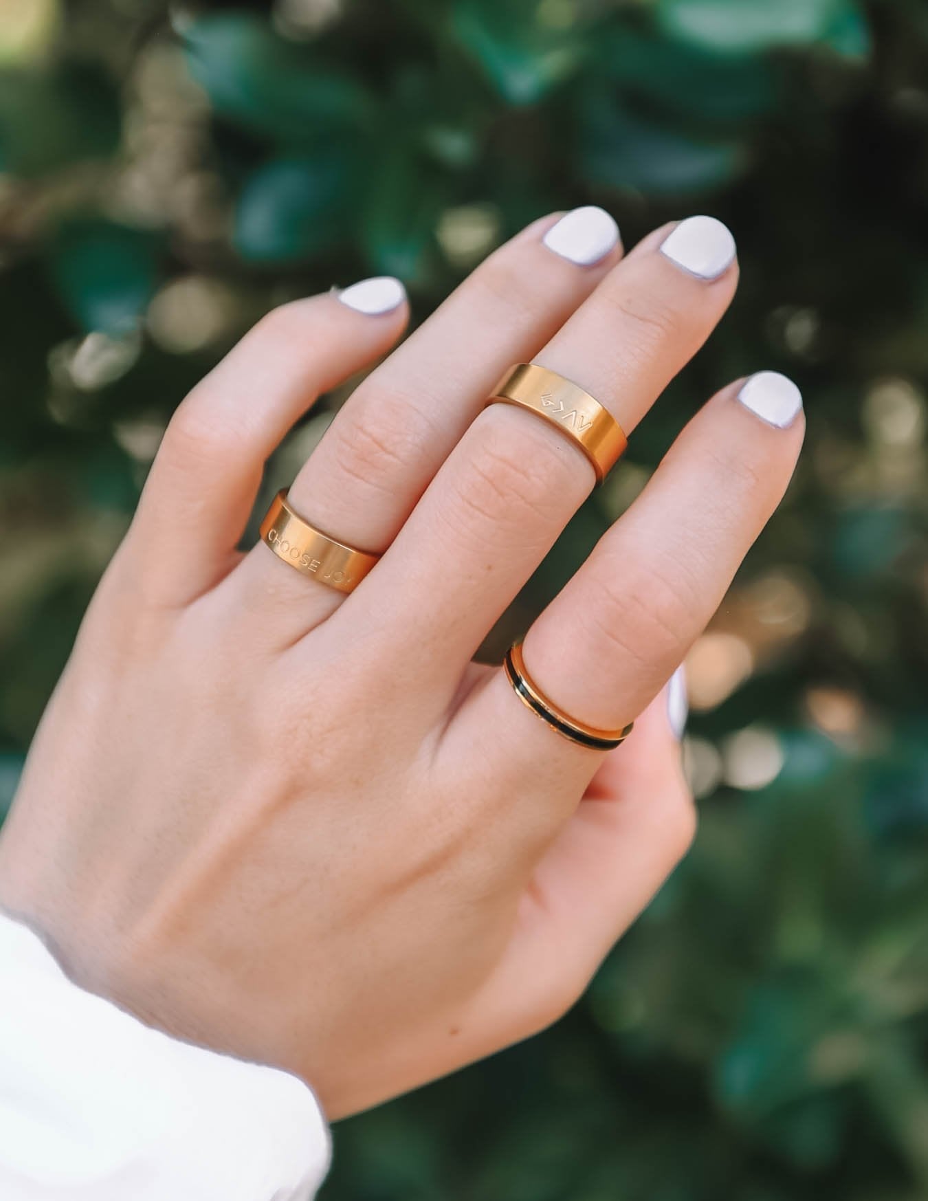 Matte gold ring with raised lettering detail on finger