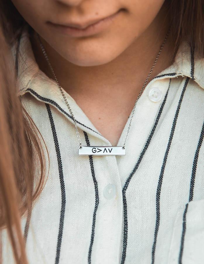 Silver chain pendant necklace with rectangular G>AV plate on striped shirt