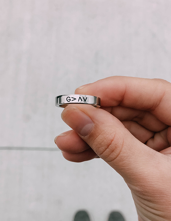 Silver ring band with black G>AV engraving on finger