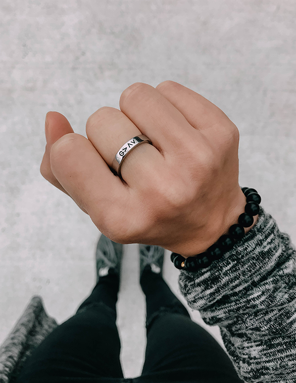 Silver ring band with black G>AV engraving on finger