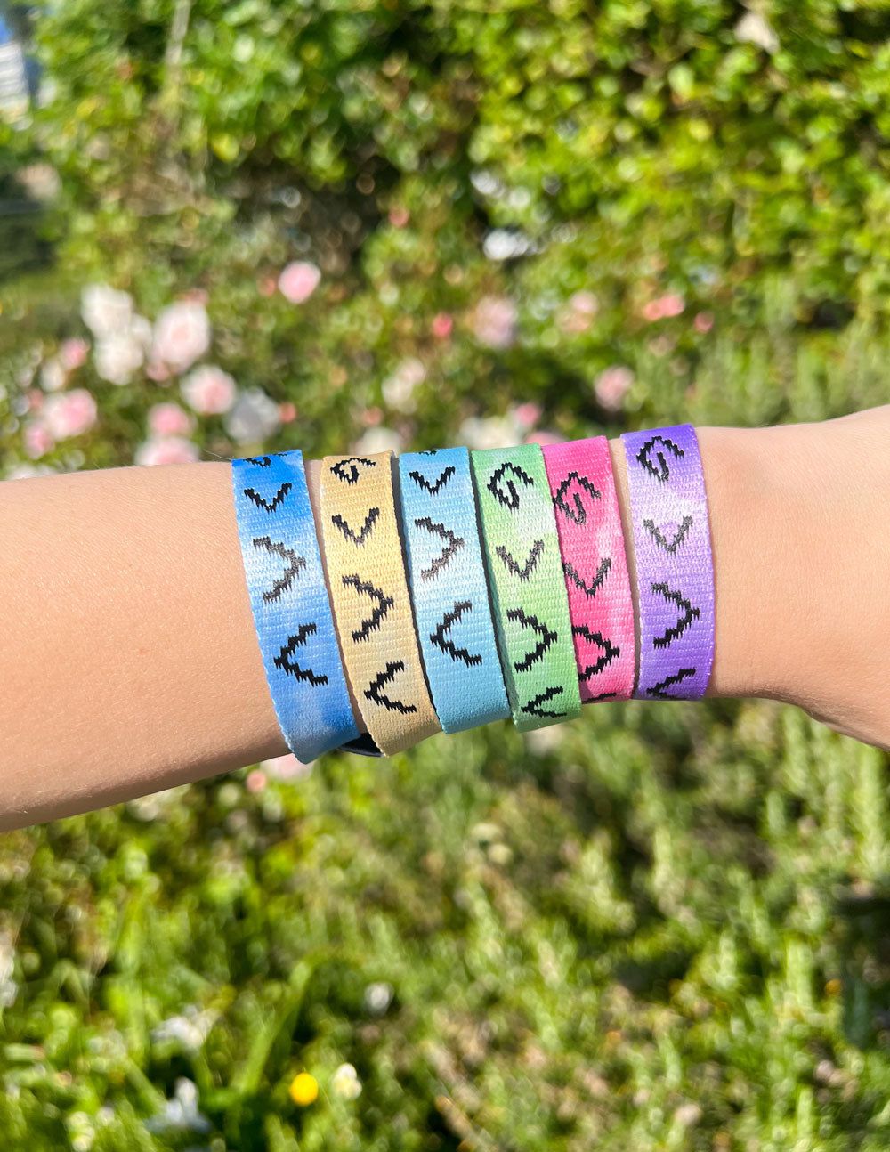 Pastel tie-dye fabric bracelets on wrist, repeating arrow-like symbols