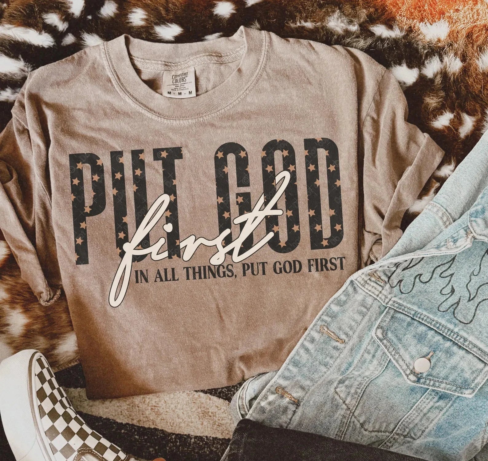 Tan crewneck T-shirt with large 'PUT GOD FIRST' front graphic and cursive text