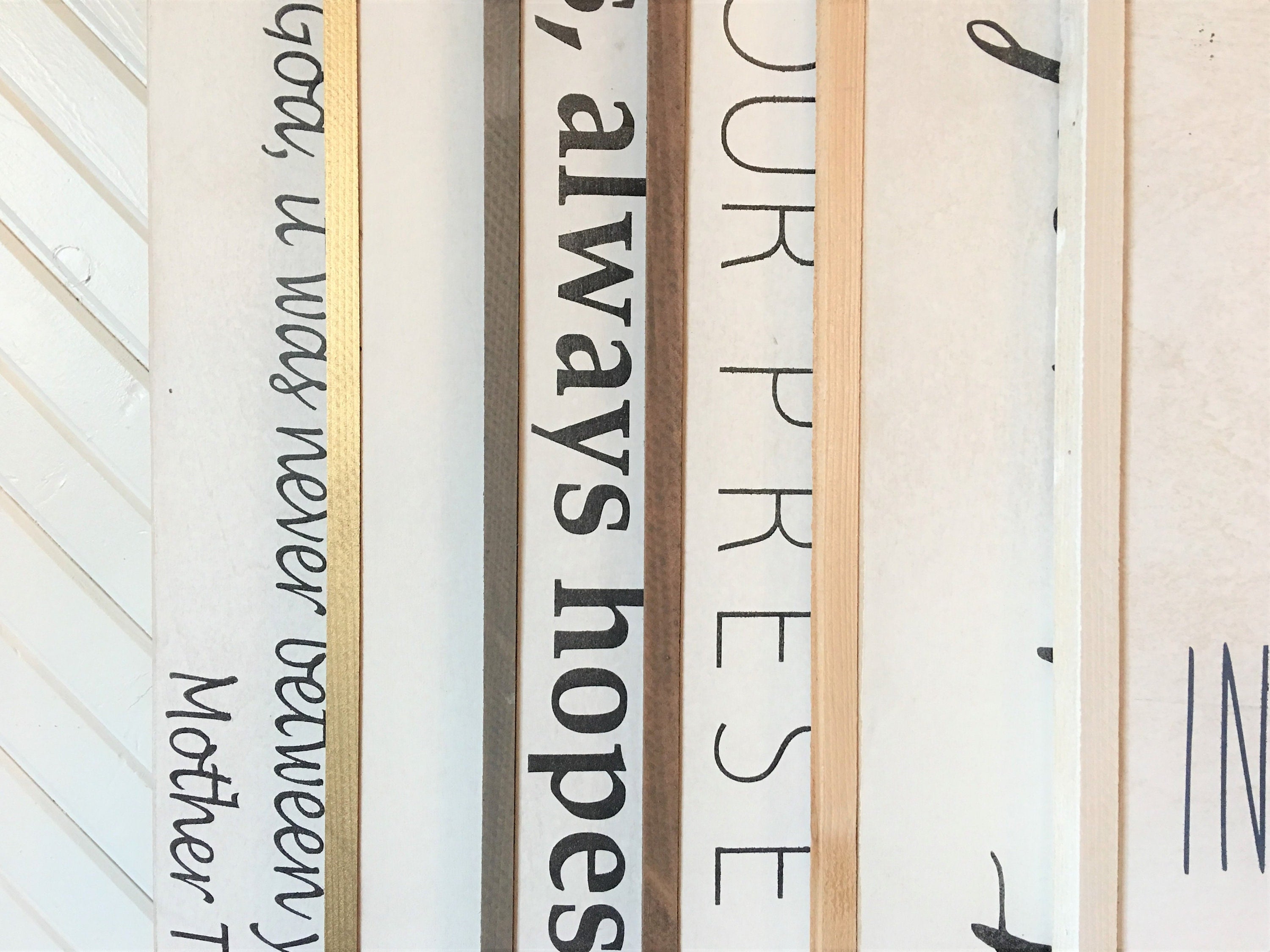 Framed wooden wall sign close-up with partial black cursive text and wood frame edge