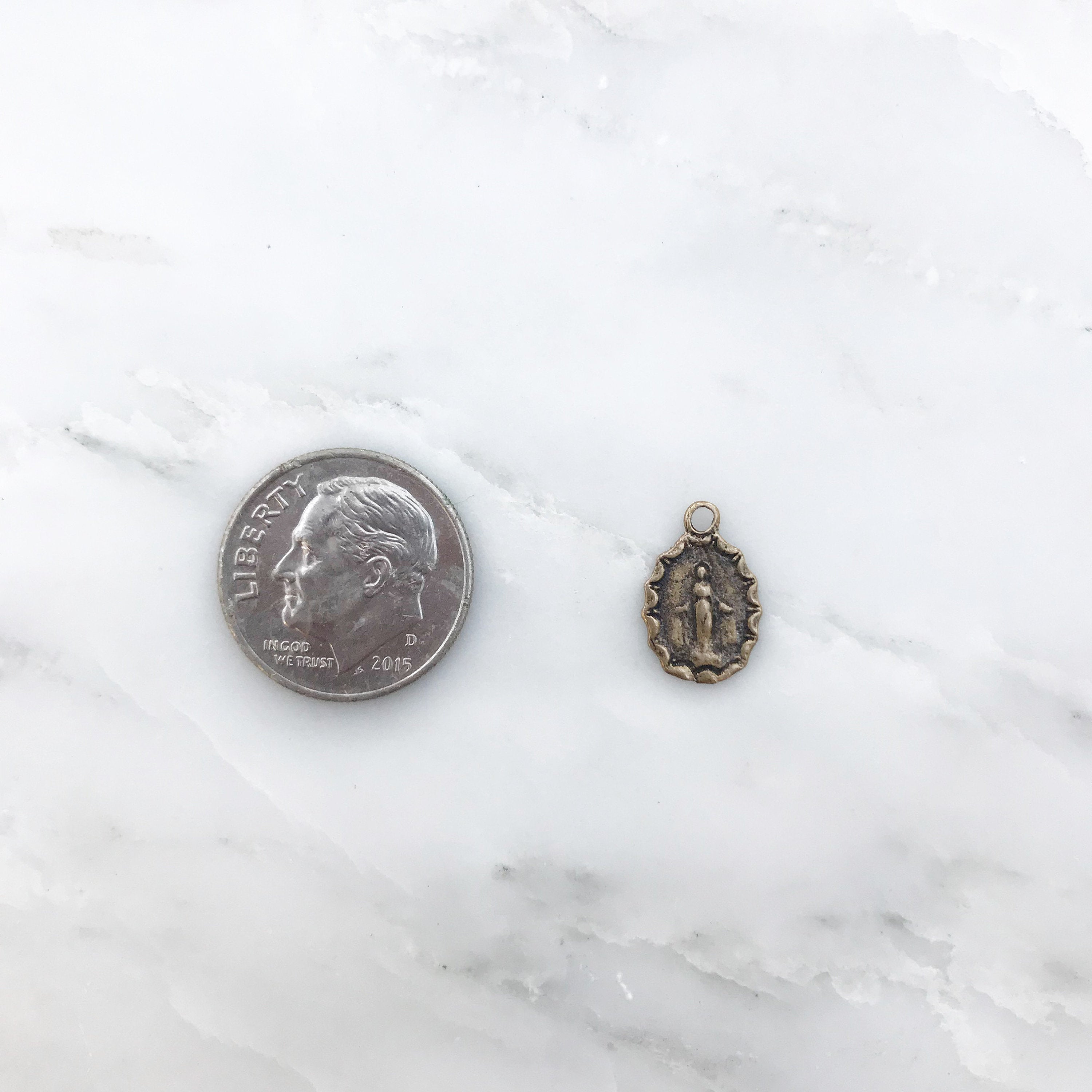 Bronze medal charm with top loop next to a dime coin for scale.