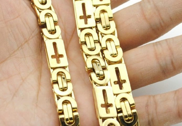Gold cross charm chain jewelry with linked bars, close-up