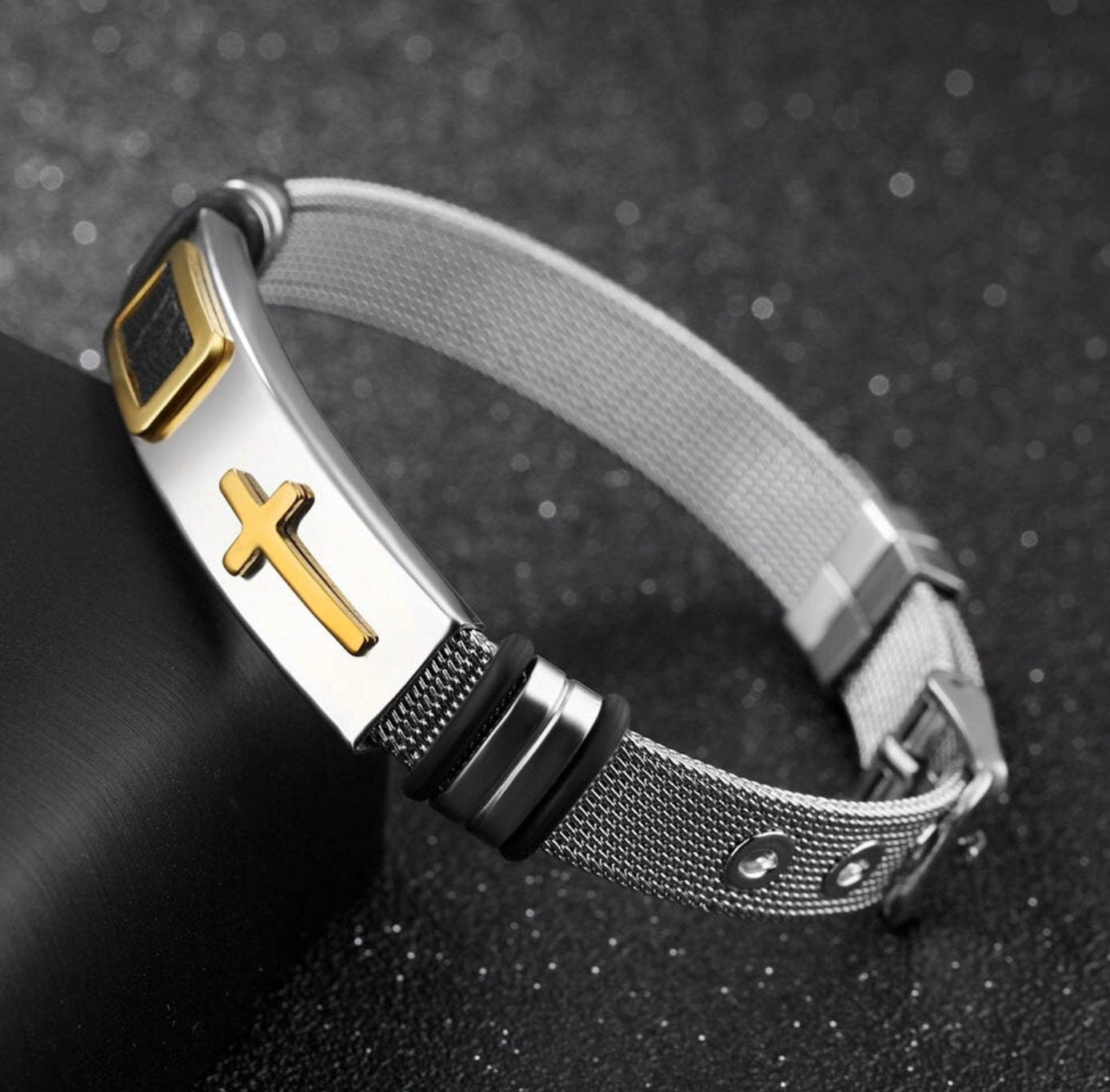 Silver mesh cross bracelet with gold cross plate, black ring accents, and clasp