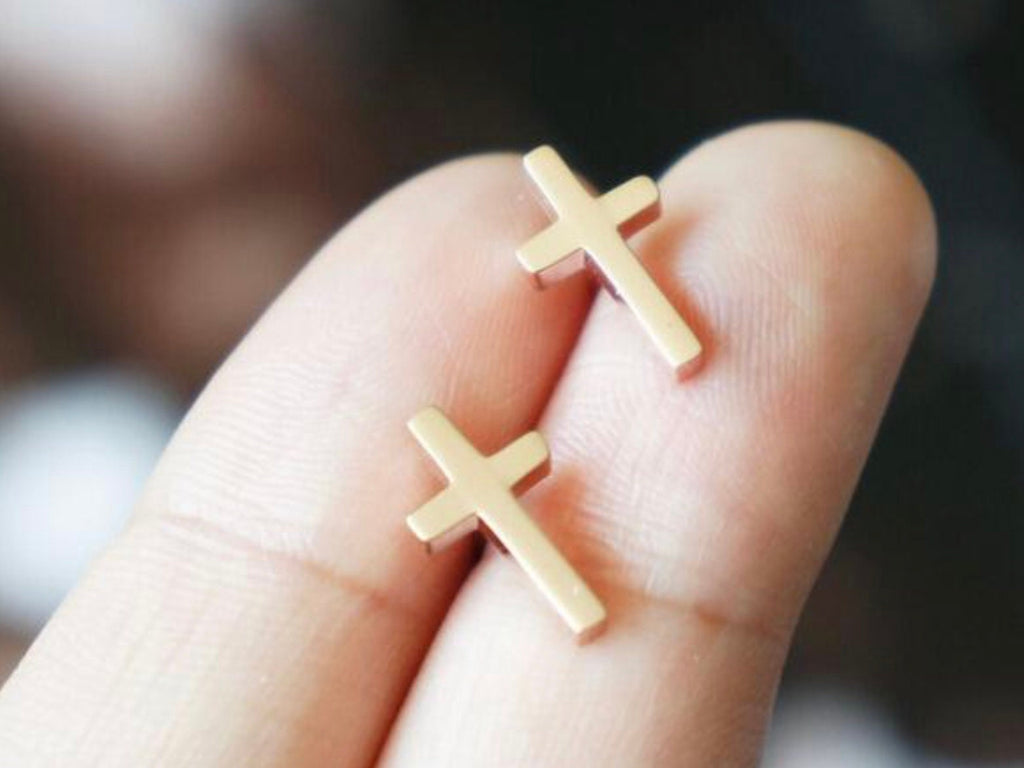 Gold cross stud earrings with post backs held in hand