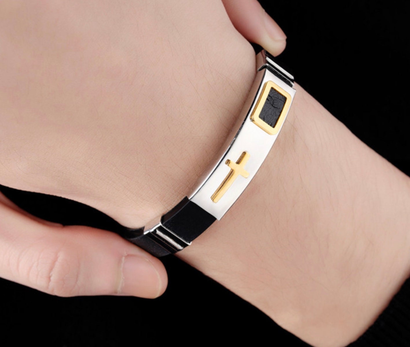 Bracelet on wrist with silver mesh band, gold cross centerpiece, and black clasp