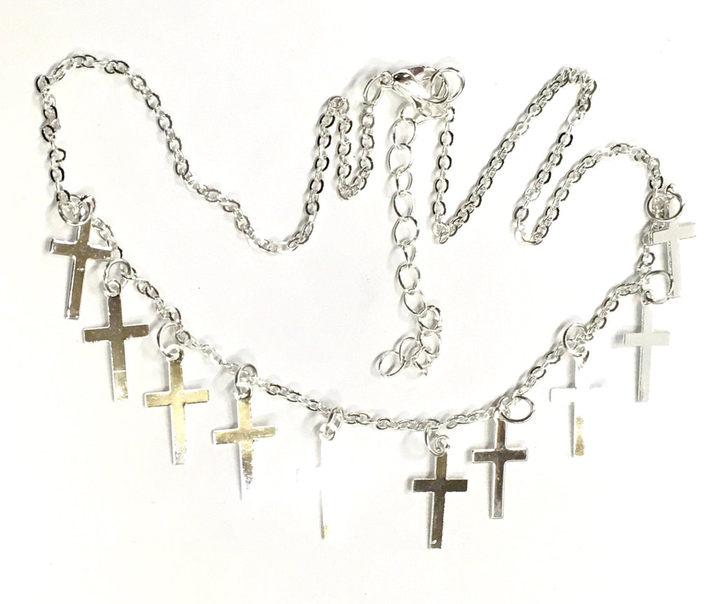 Silver-tone cross necklace and earring set with small cross charms, flat lay