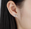 Jesus stud earrings in gold script, close-up on ear with hair framing
