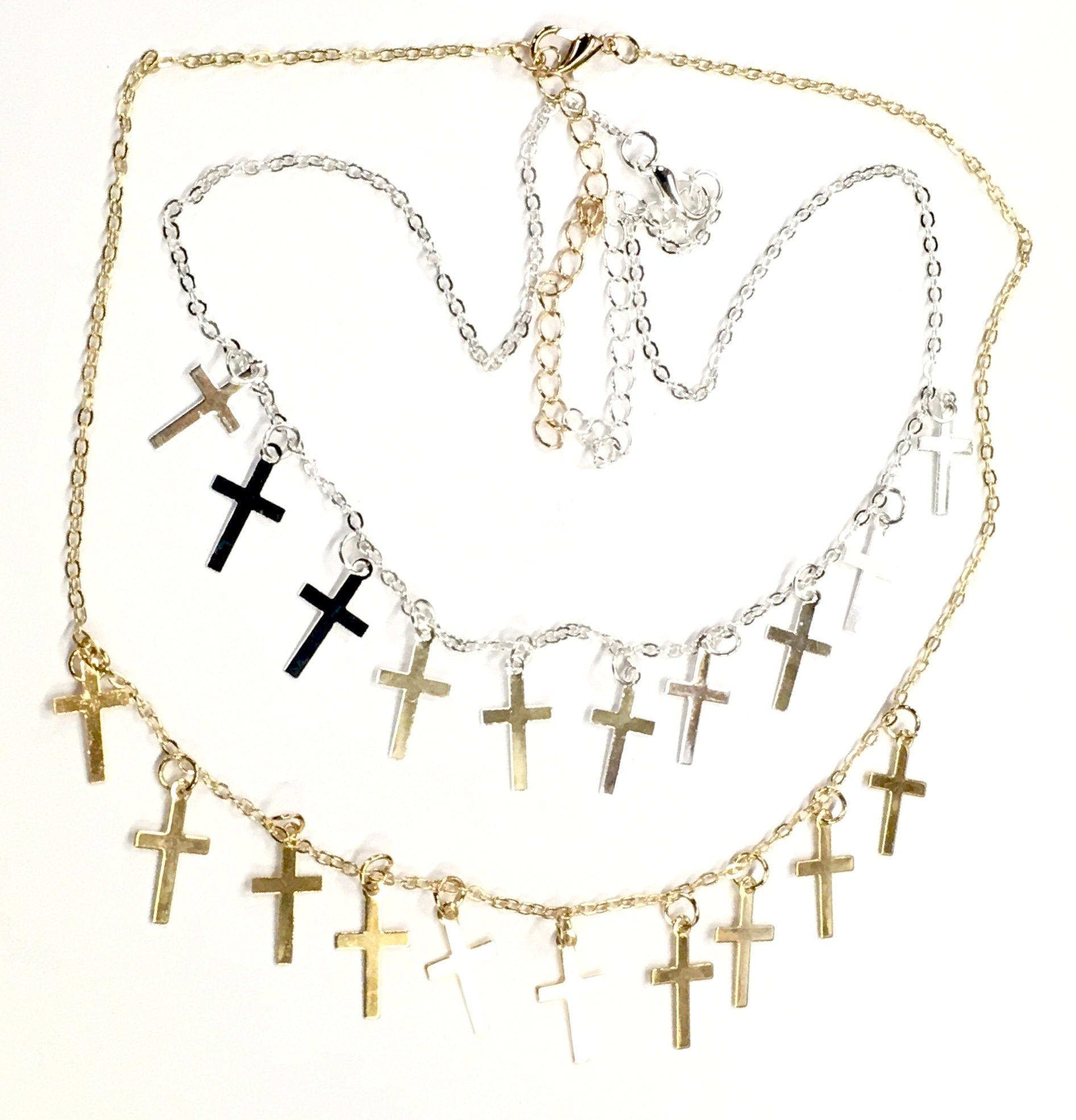 Gold and silver-tone cross necklace and earring set with small cross charms, flat lay