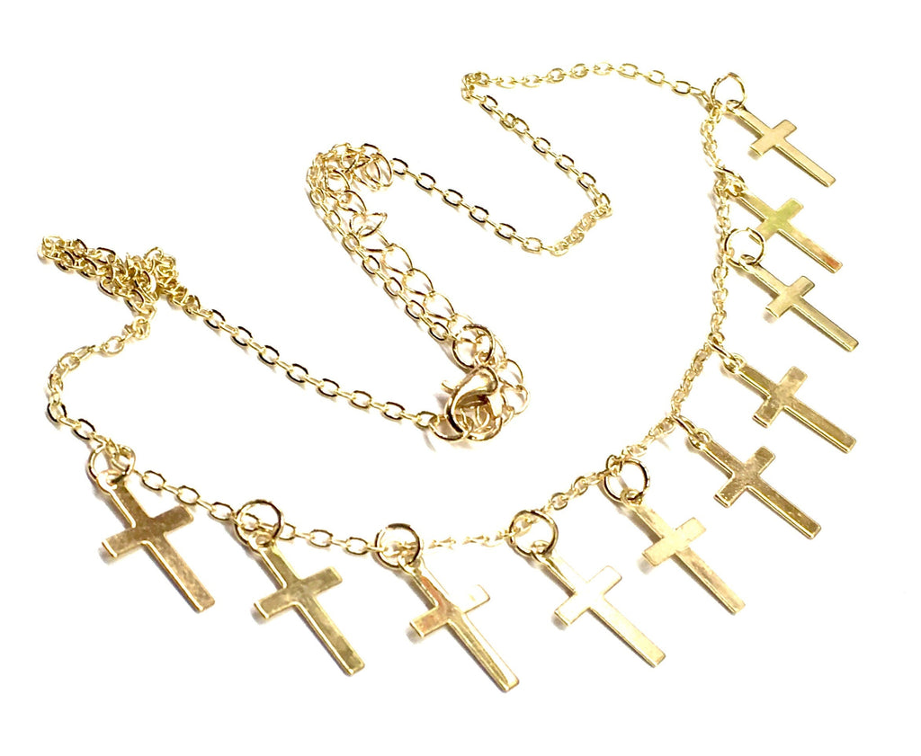 Gold-tone cross necklace and earring set with multiple small cross charms, flat lay