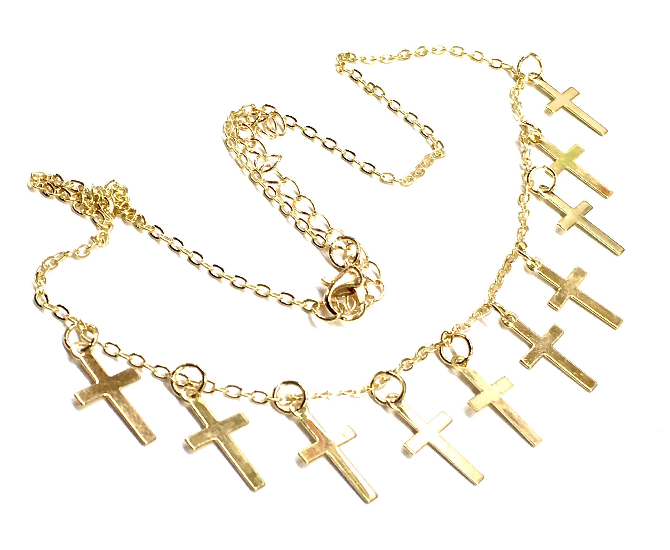 Gold-tone cross necklace and earring set with multiple small cross charms, flat lay