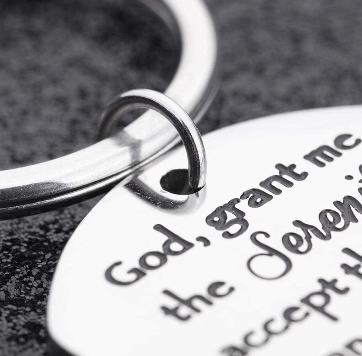 Closeup silver keyring dog tag showing engraved Serenity Prayer lettering.