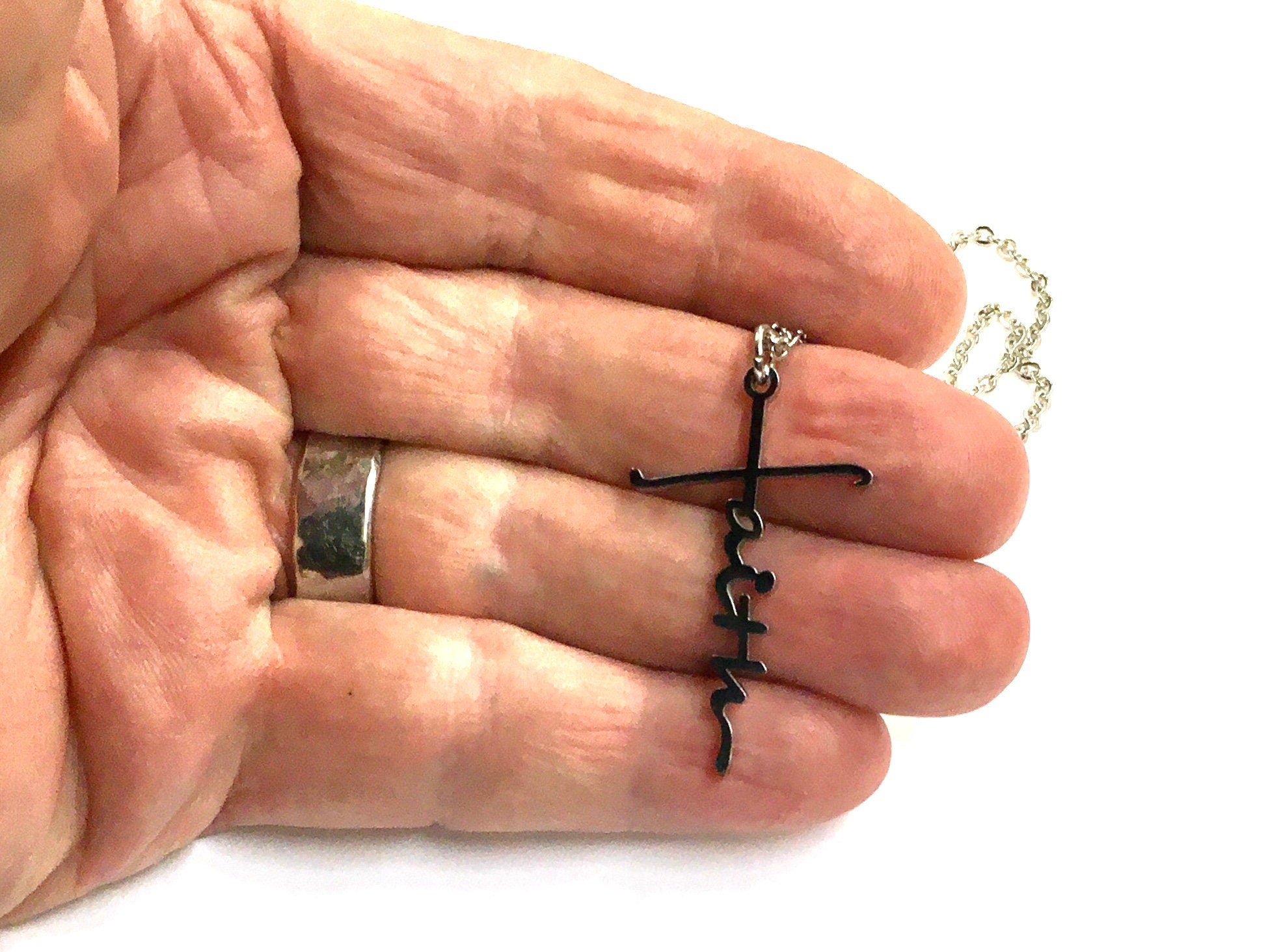 Silver cross pendant necklace held in hand with chain