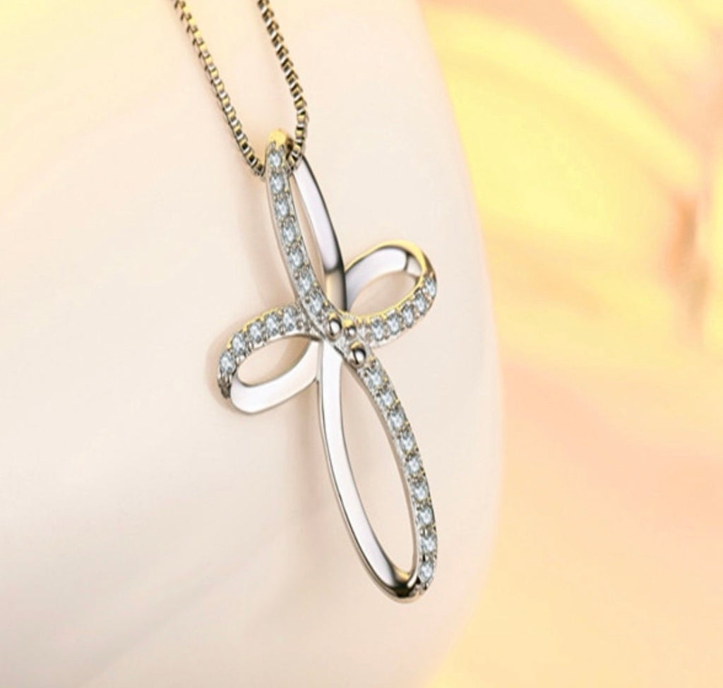 Two-tone swirl cross pendant necklace with clear stones on a chain