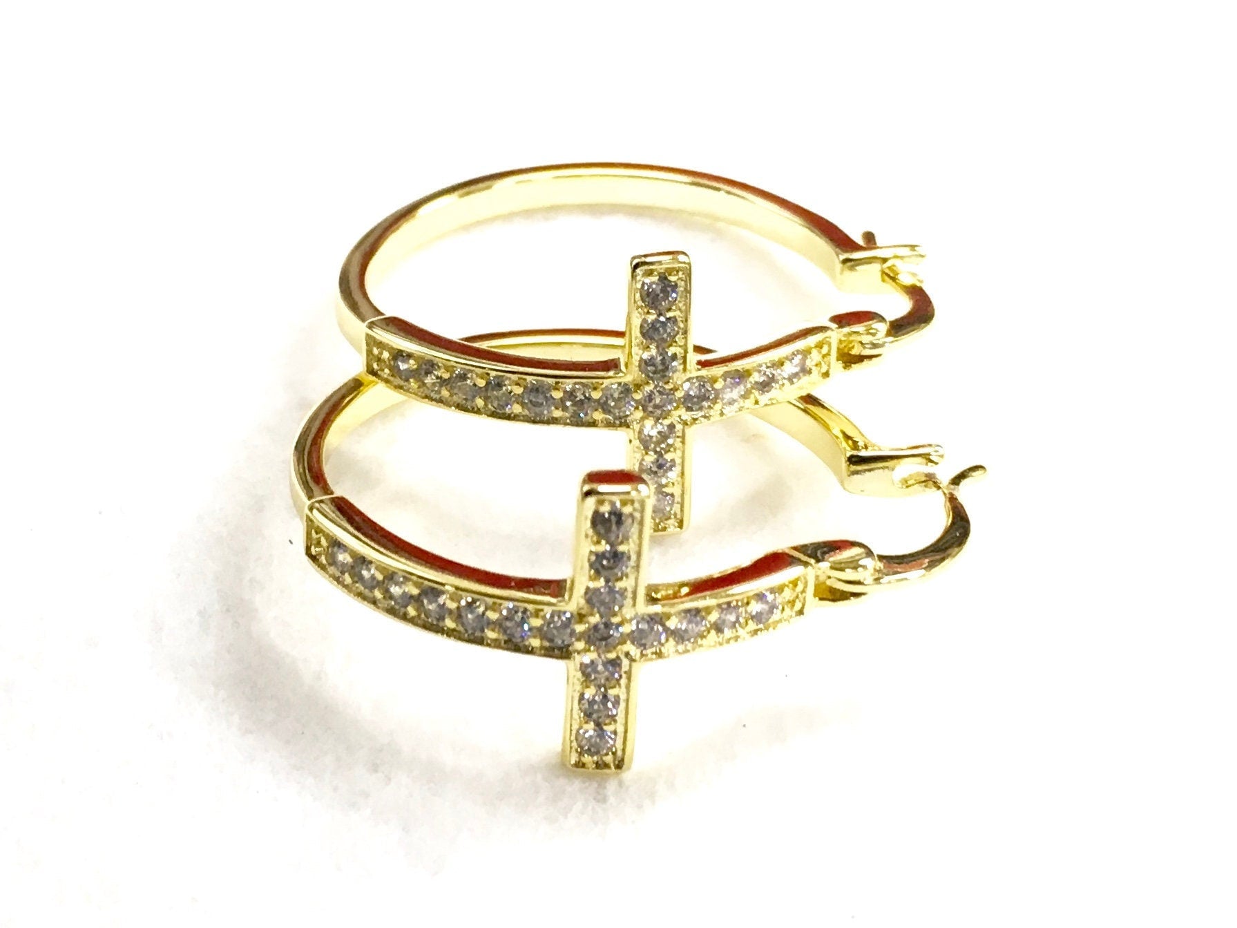 Gold cross hoop earrings with round pavé cross centerpiece and hinged hoop