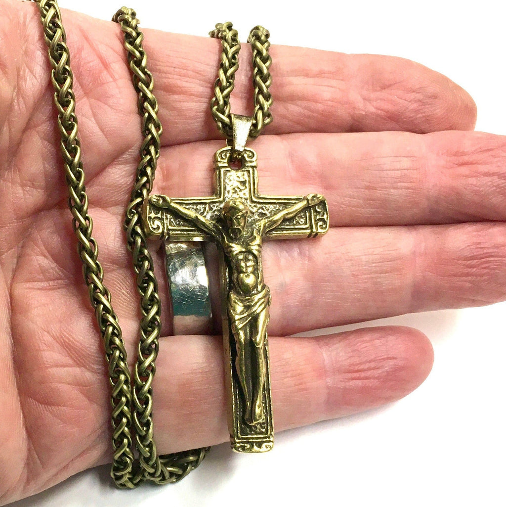Bronze crucifix pendant necklace with heavy chain held in palm.