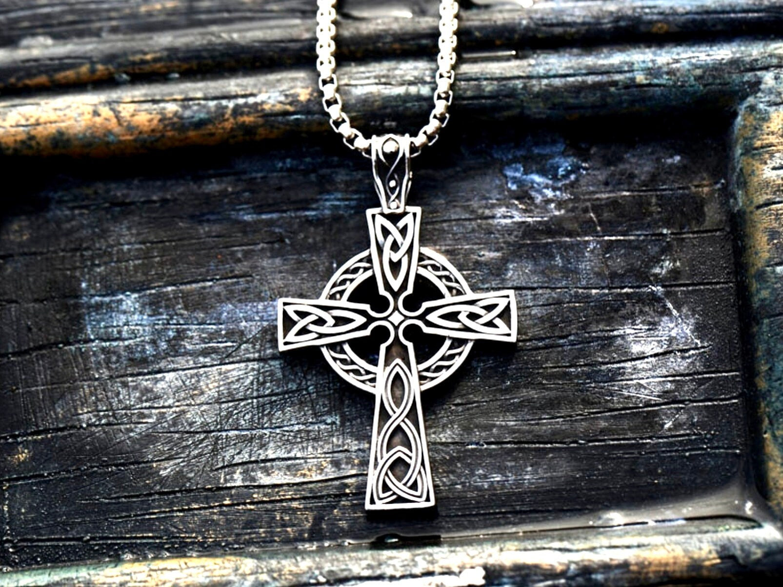 Silver Celtic knot cross pendant necklace on a dark wooden surface