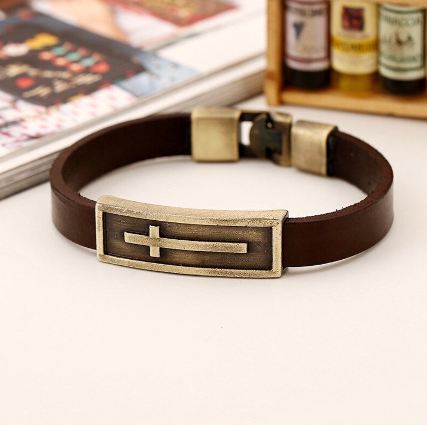 Brown leather cross bracelet with gold-tone buckle and rectangular cross centerpiece