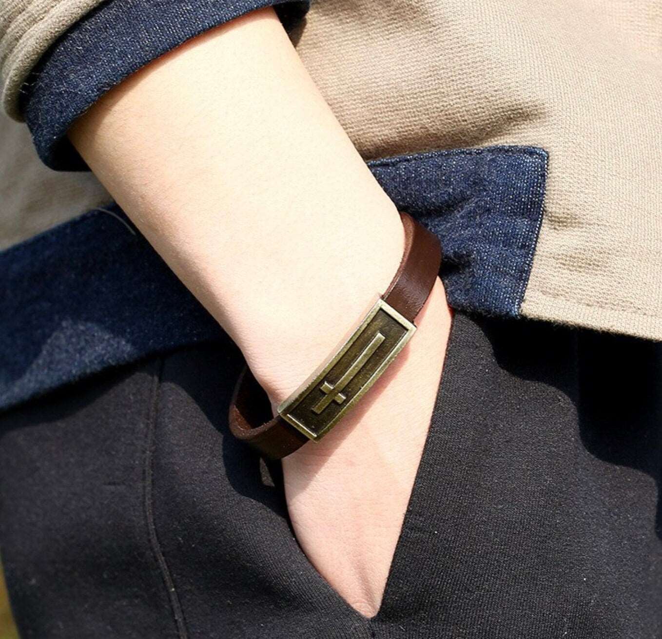 Leather cross bracelet on wrist with gold-tone clasp and cross cutout