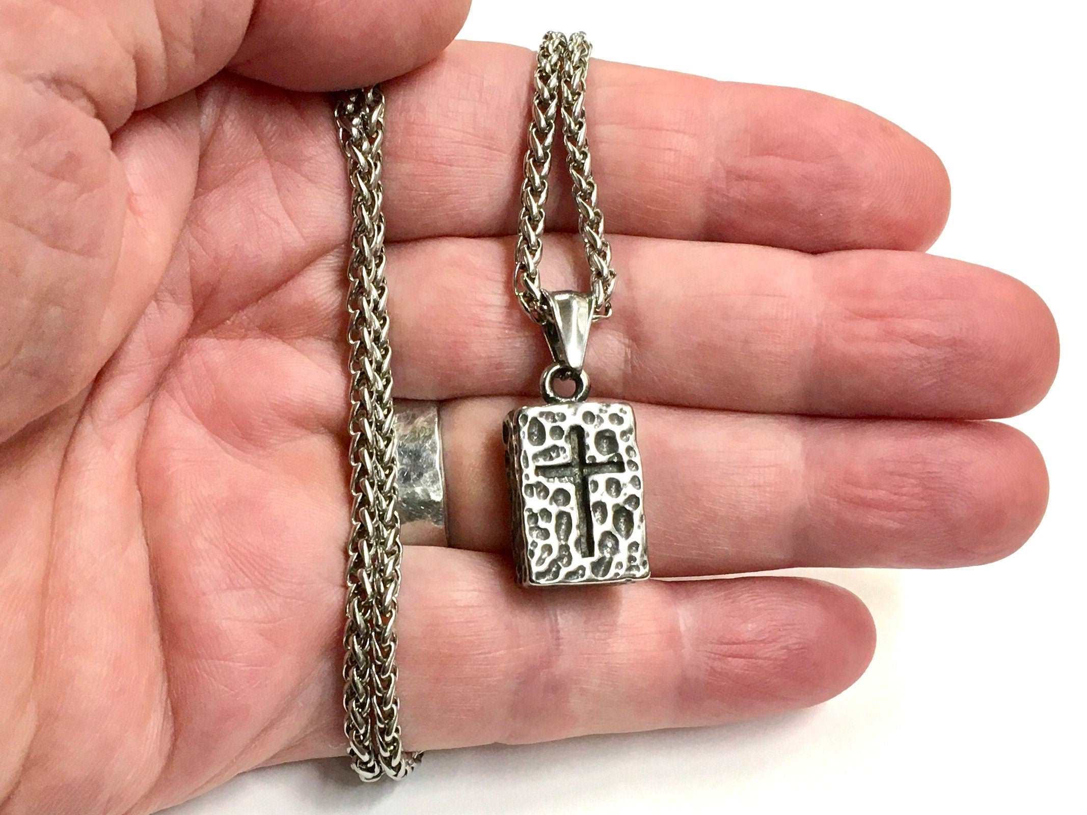 Stainless steel hammered cross rectangle pendant with curb chain, held in hand