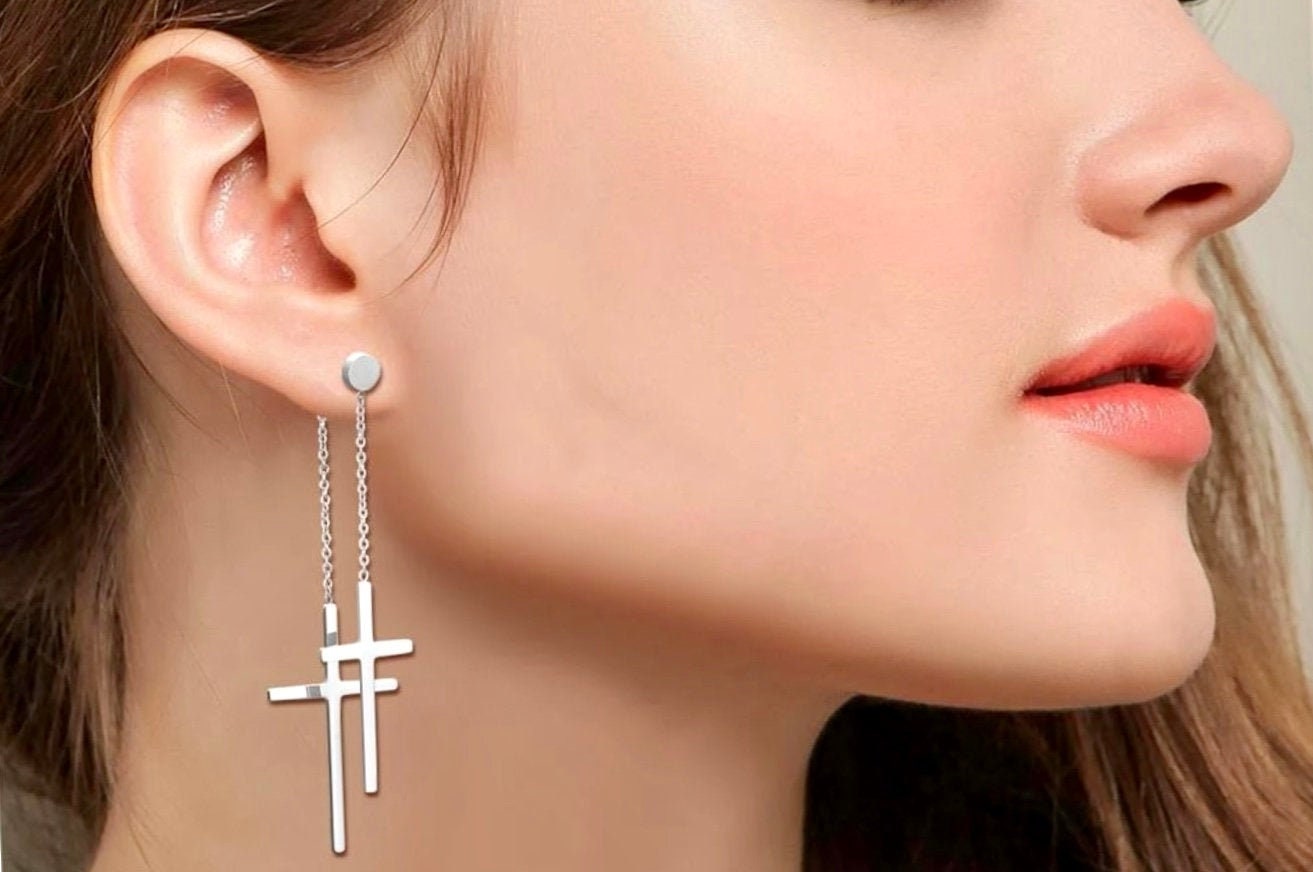 Silver double cross drop earrings with chain tassels, close-up on ear