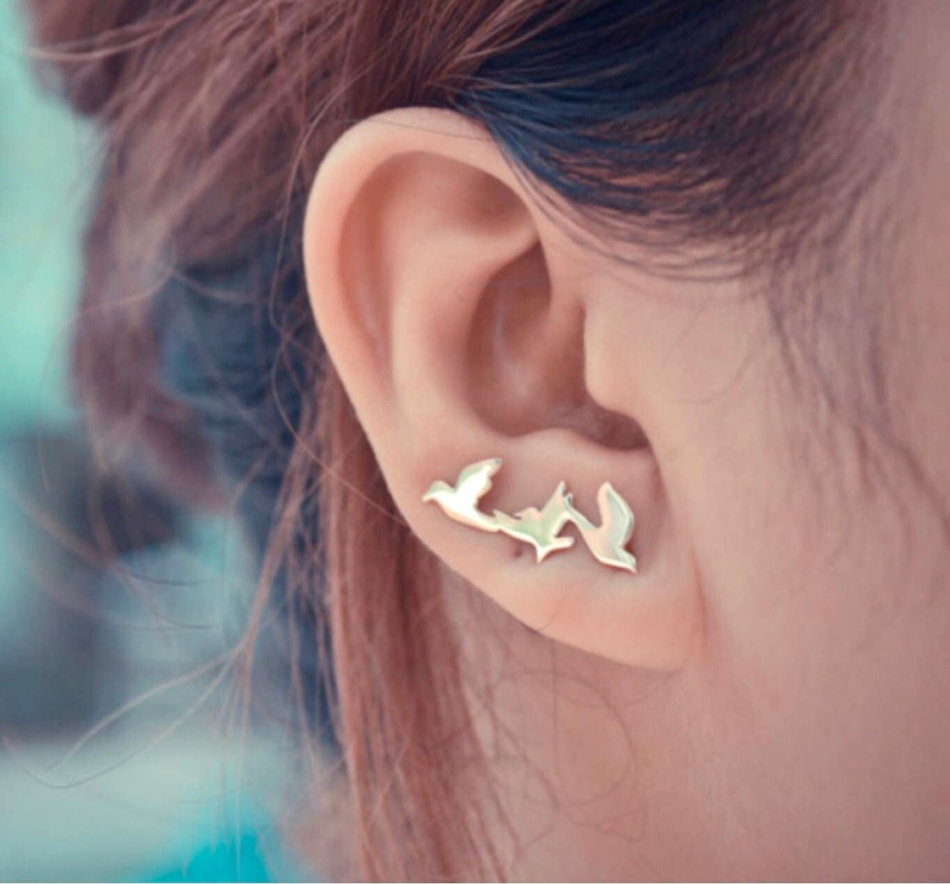 Gold dove ear climber stud earrings on a model ear, side view