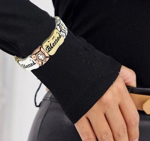 Gold-tone stretch bracelet cuff with stamped cross and “Blessed” text panel