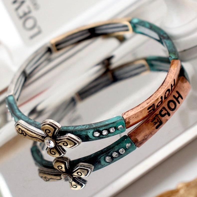 Teal stretch bracelet cuff with gold cross charm, engraved details, and rhinestones