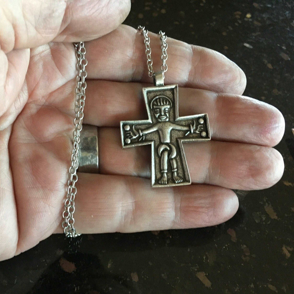 Silver cross pendant on chain, Jesus figure centered, held in hand