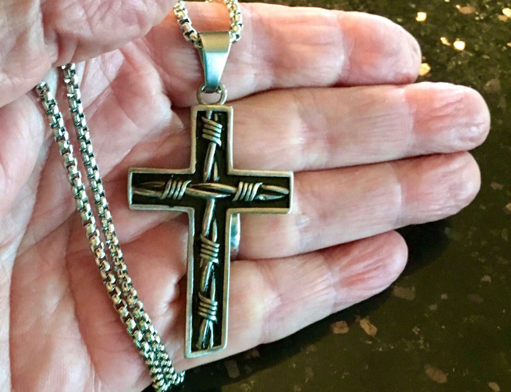 Crucifix cross pendant necklace held in hand with silver chain and dark cross
