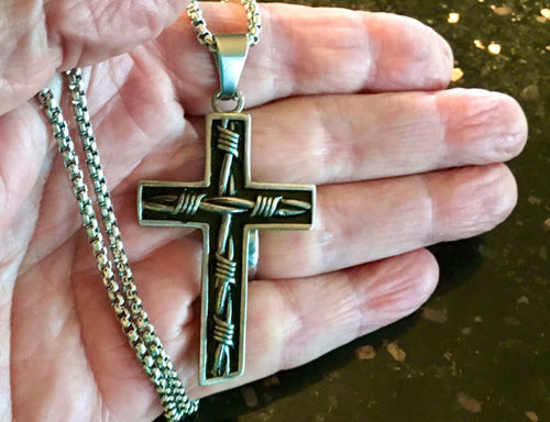Crucifix cross pendant necklace held in hand with silver chain and dark cross