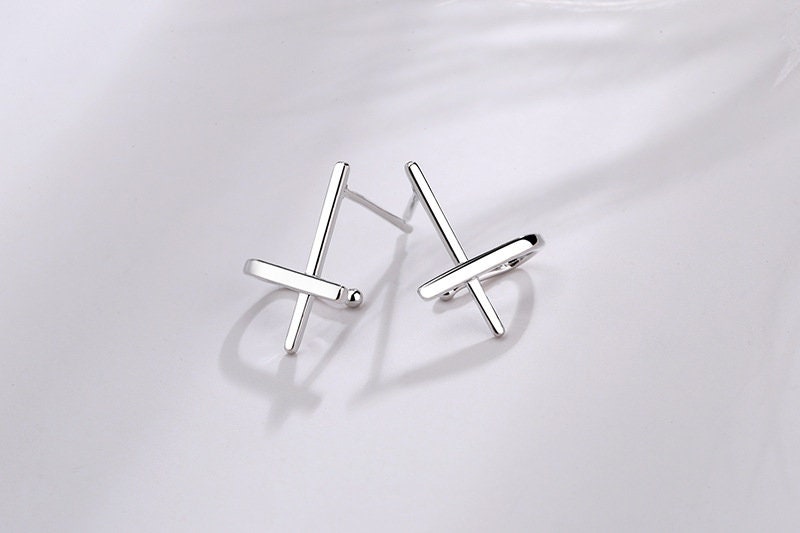 Sterling silver cross huggie stud earrings with small cross bars, angled