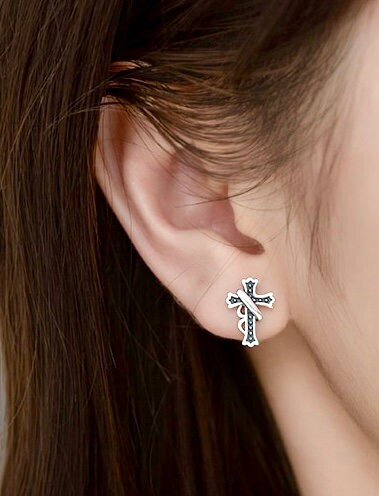 Sterling silver cross stud earrings with blue enamel and filigree on a wearer's ear