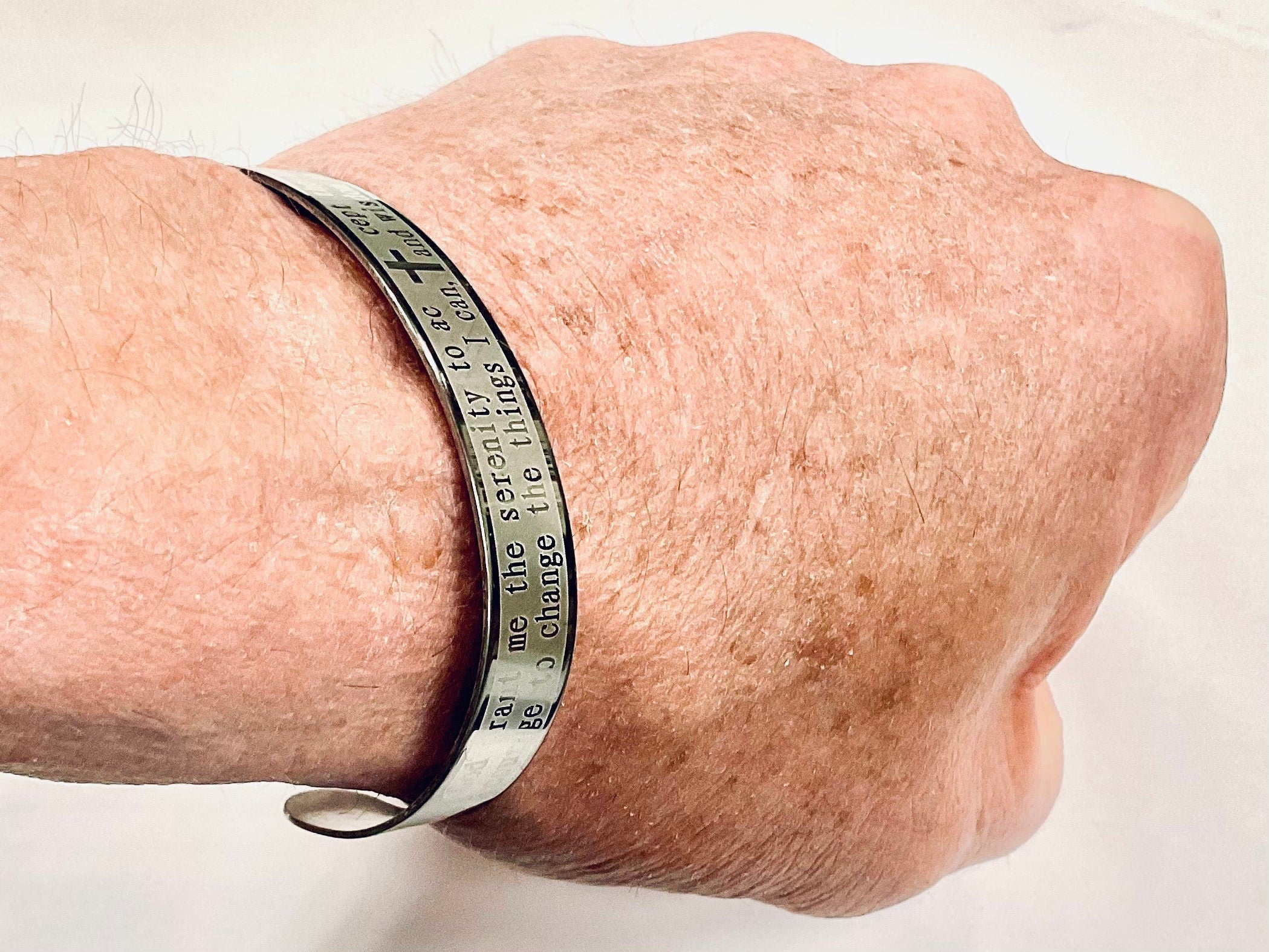 Stainless steel prayer cuff bracelet engraved with words on wearer’s wrist