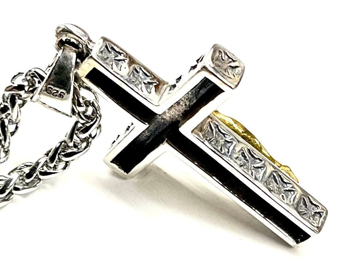 Crucifix cross pendant with silver frame, gold-tone figure, and black center inlay