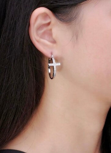 Silver cross hoop earrings with small rhinestone detail, worn in-ear