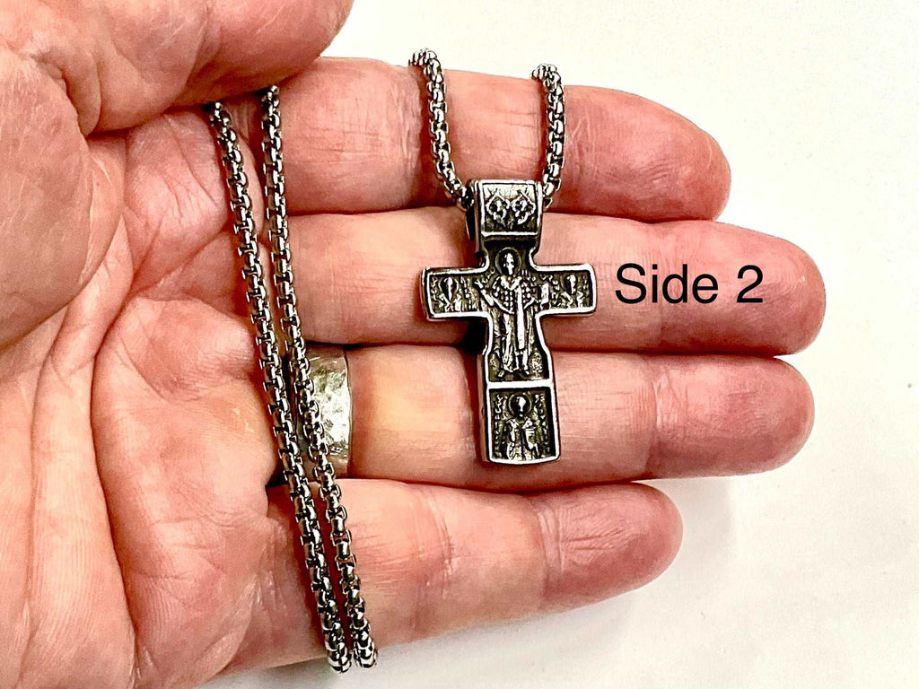 Silver crucifix cross pendant necklace held in a hand with second-side design