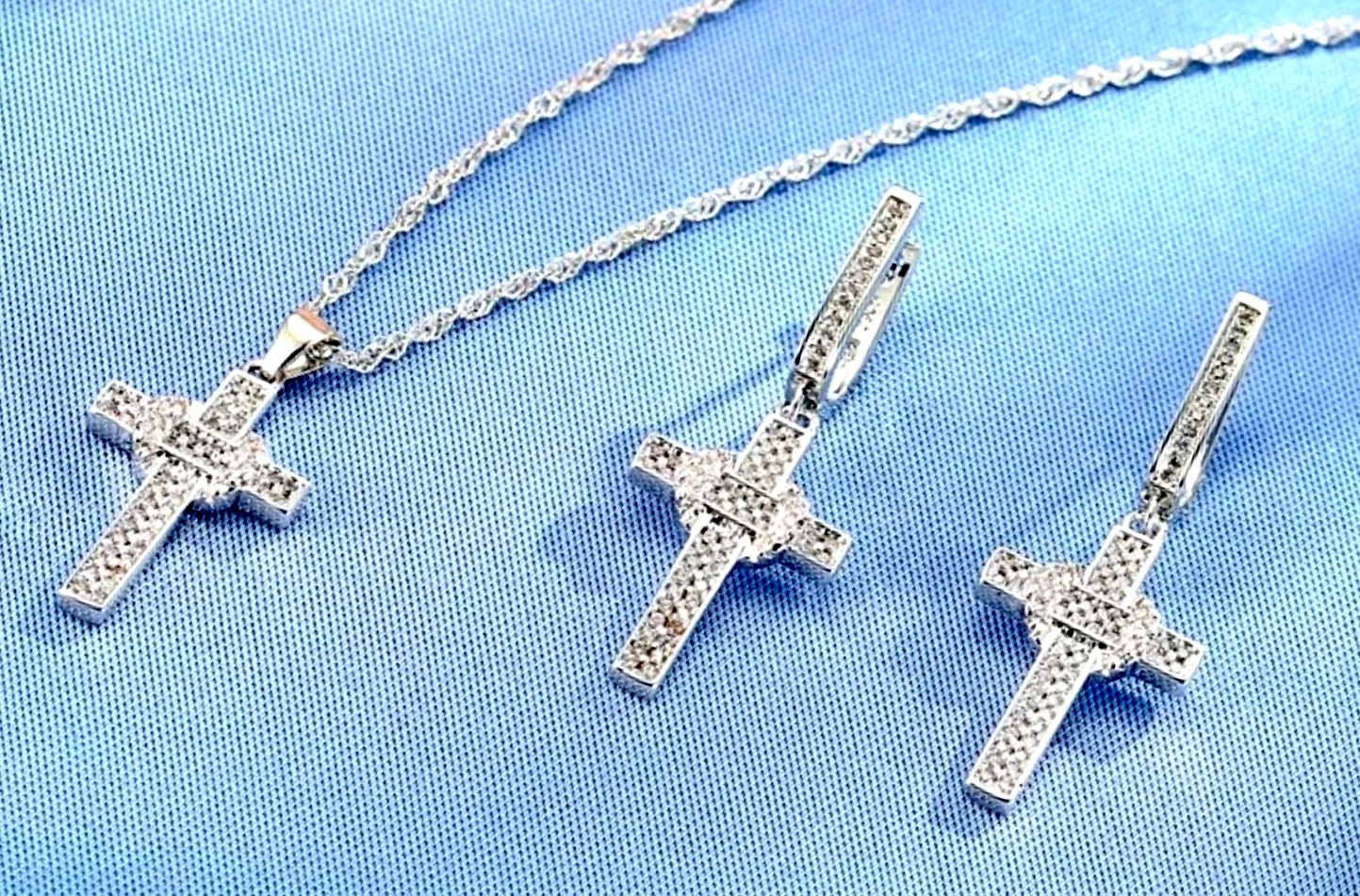 Sterling silver zircon cross pendant and earrings with link chain on blue fabric