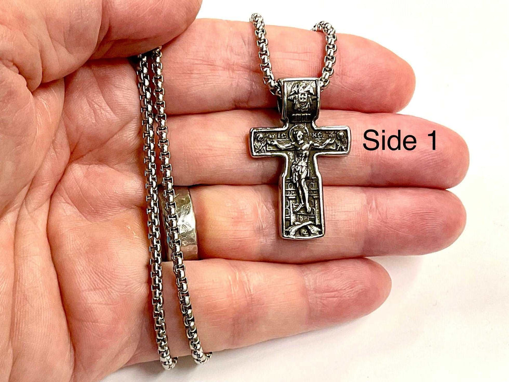 Silver crucifix pendant necklace held in a hand with chain and clasp