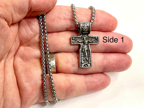 Silver crucifix pendant necklace held in a hand with chain and clasp