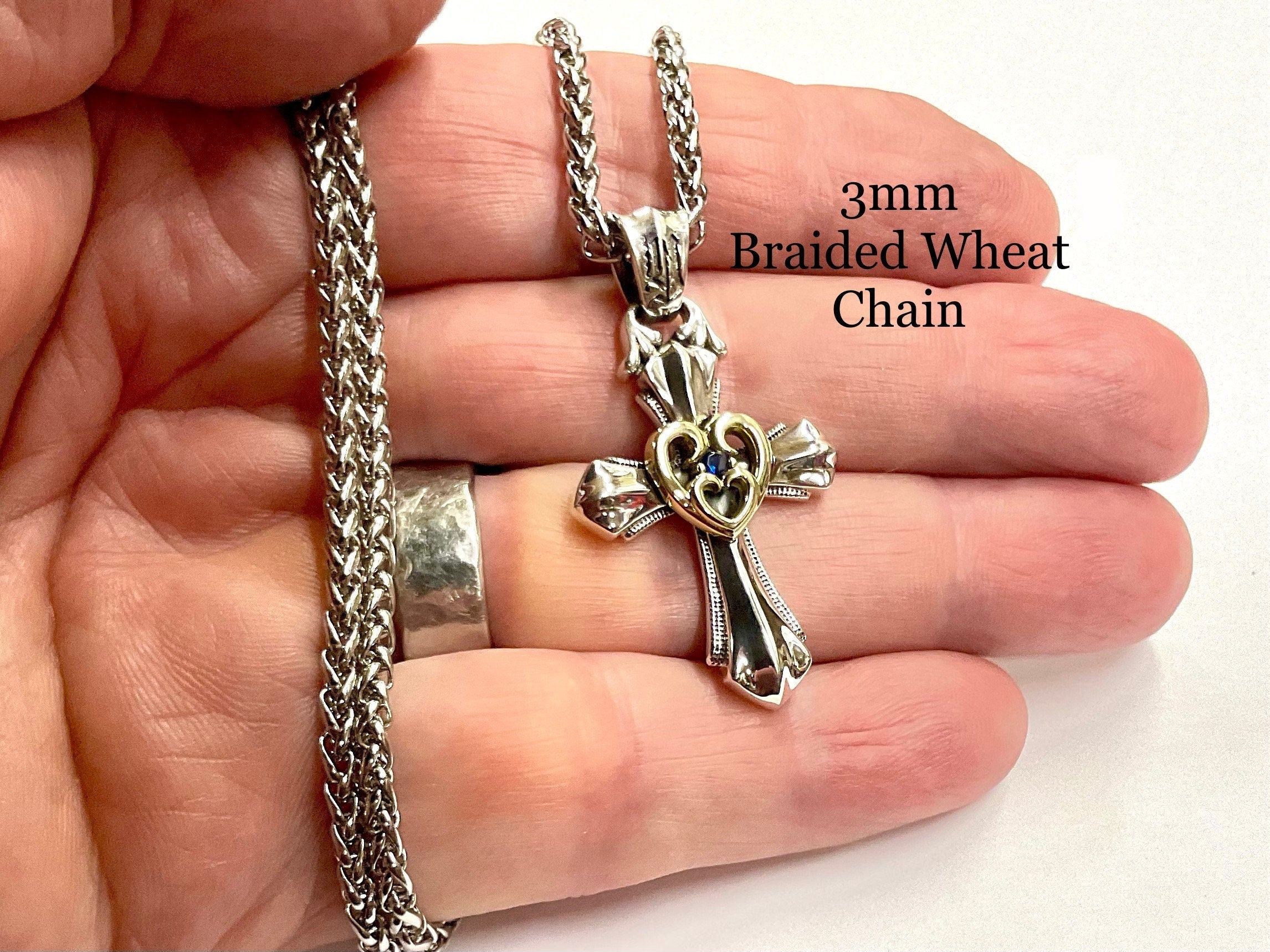 Sterling silver cross necklace with open heart charm and blue zircon, close-up