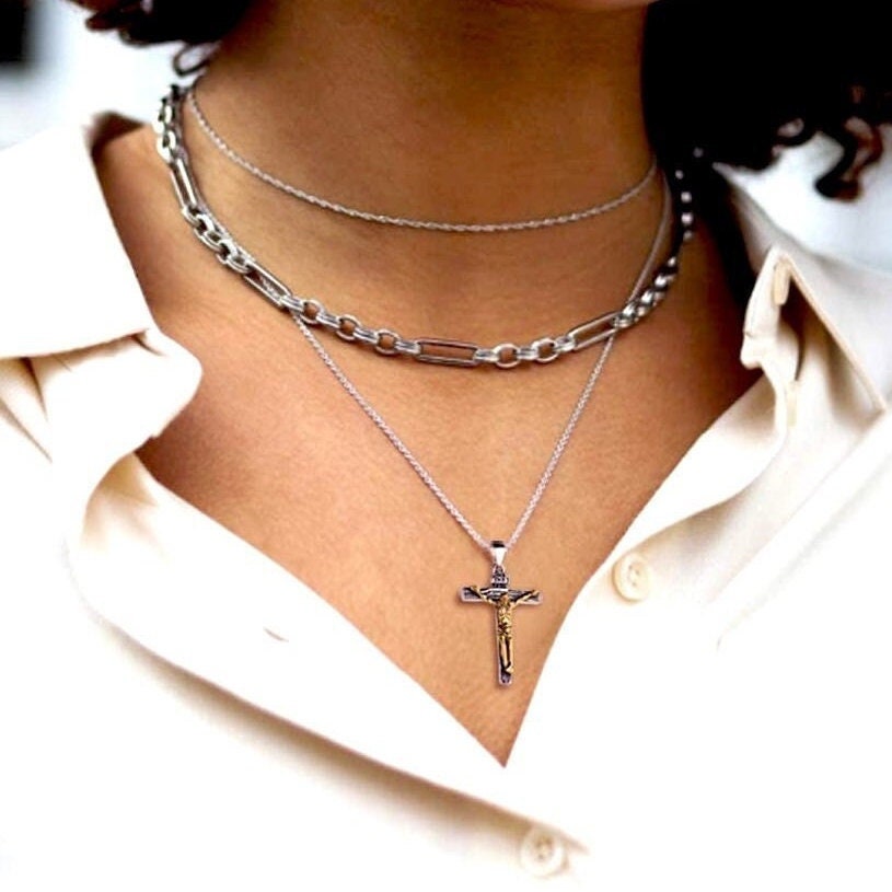 Silver crucifix necklace with small pendant, worn on white shirt