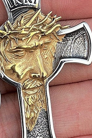 Close-up of silver and gold Jesus crucifix pendant with INRI plaque and thorns