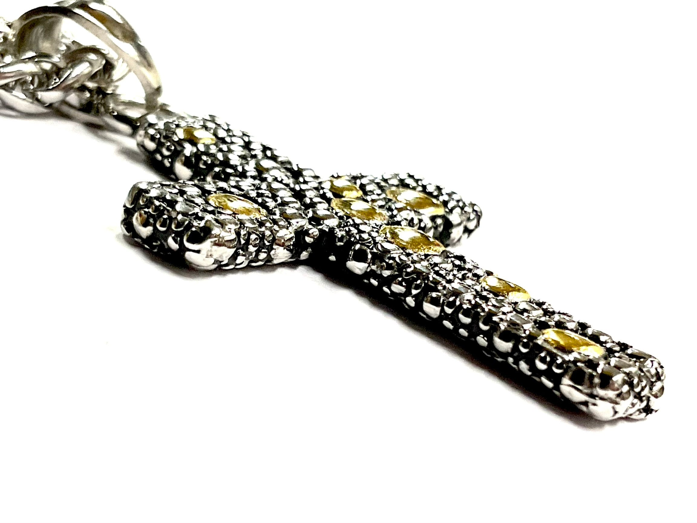 Stainless steel crucifix pendant side detail with yellow stones on chain.